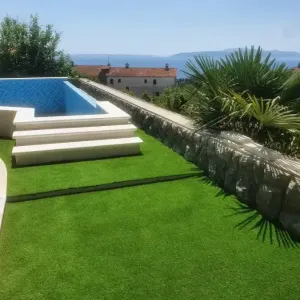 Bazen okružen zelenom umjetnom travom i pogledom na more