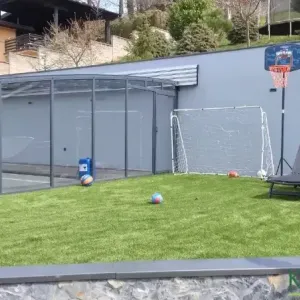 Gol i ko&scaron; za ko&scaron;arku kraj staklene nadstre&scaron;nice i zelene trave