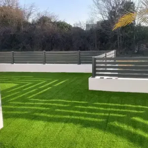 Siva ograda oko dvori&scaron;ta sa umjetnom travom